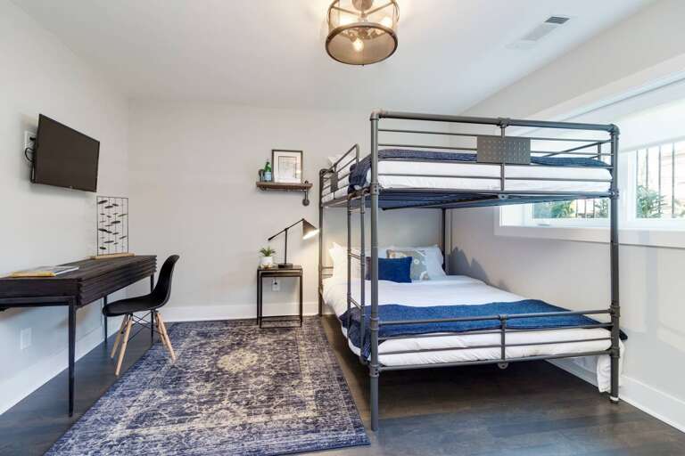 - Metal queen over queen bunk bed, dressed in crisp white &amp; navy linens - Dedicated desk &amp; reading lamp offer the perfect nook for remote work or journaling - Cozy navy rug, sleek décor, &amp; wall mounted TV bring comfort &amp; function together