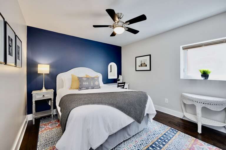 - Unwind in this stylish sanctuary featuring a bold navy accent wall and inviting bed - Start your day in a bright, airy space designed for comfort and relaxation - Elegant details and modern vibes create a true home away from home