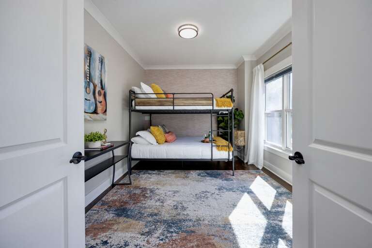 - Step into this fun, sun filled bunk room, perfect for kids or the young at heart - Comfortable beds, playful pillows, and a bold rug create a space full of personality - Bright window light and guitar wall art complete the vibe