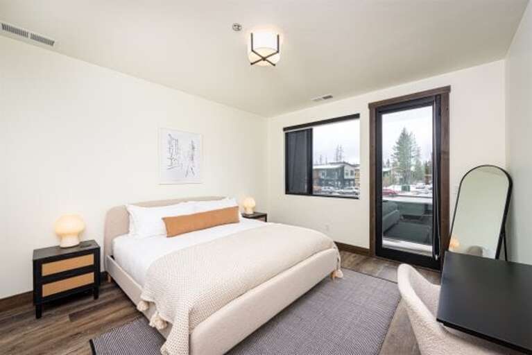 The chic primary bedroom features a king-size bed, private balcony, dedicated work space & luxurious ensuite | Main Level