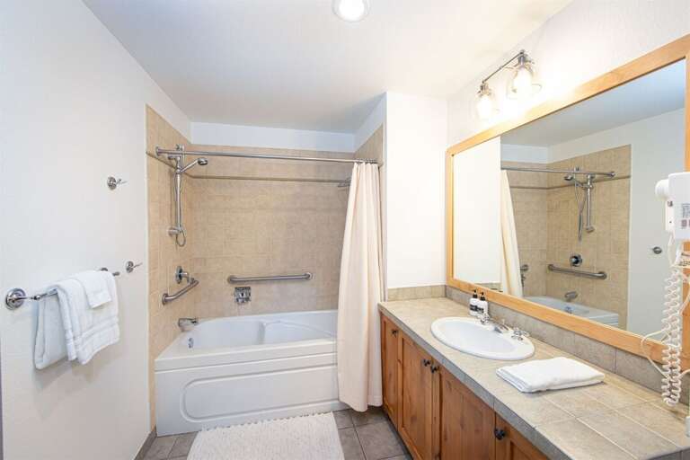 The guest bathroom has an oversized vanity, bathtub & laundry area | Main Level