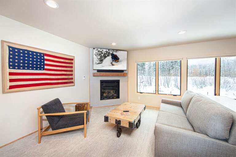 The ground floor living room has a television, a fireplace & sleeper sofa | Basement Lowest Level