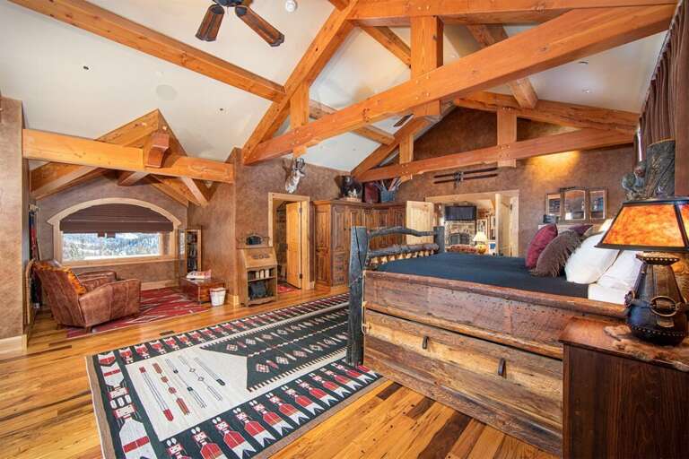 The ante room leading into the primary master suite features a king-sized bed, a seating area & full bathroom | Upper Level