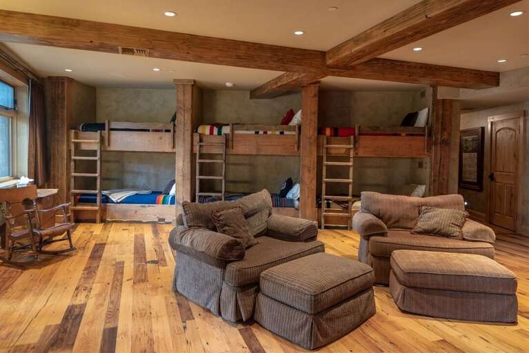 The bunk room features custom-built-in bunk beds, a television & seating, a kitchenette & dining area | Lower Level