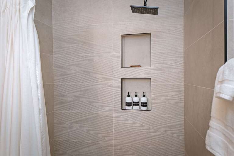 The main bathroom has a shower with bathtub & custom tile | Main Level