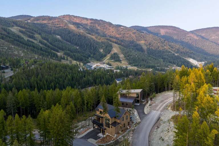Aerial View Of Wooded Valley With Buildings And Winding Road