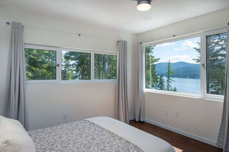This bedroom on the main floor of the home, features a queen size bed, ensuite & incredible views | Main Floor