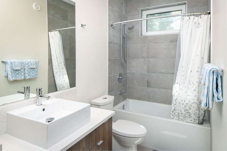 The shared bathroom features modern fixtures and a bathtub | Upper Level