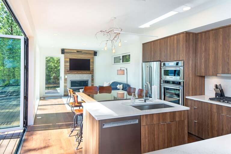 The open concept kitchen, dining & living room is framed by accordion style doors that bring the outdoors within | Main Floor