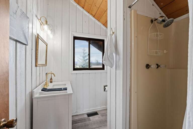 Well lit bathroom with freestanding shower and single vanity | Upper Level