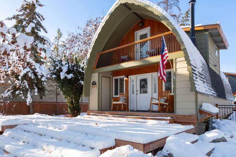 Snow-swept Steps Leading To A Quaint House With An American Flag