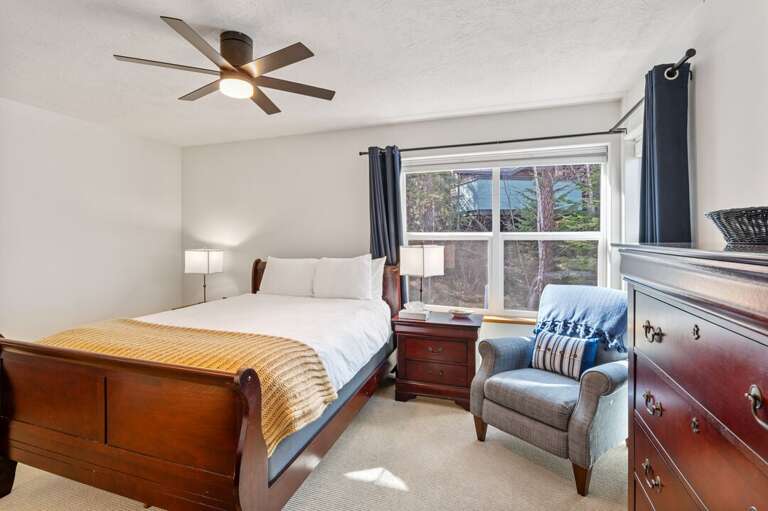 Master bedroom with queen bed, accent chair, 45" smart tv, and ensuite bathroom