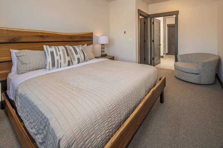 Primary bedroom with a king-size bed and additional seating. | Main Level