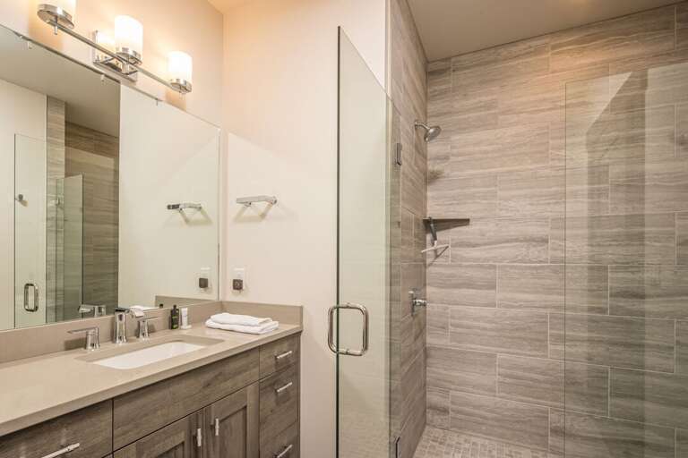 The shared full bath with a single vanity and a walk-in shower. | Main Level