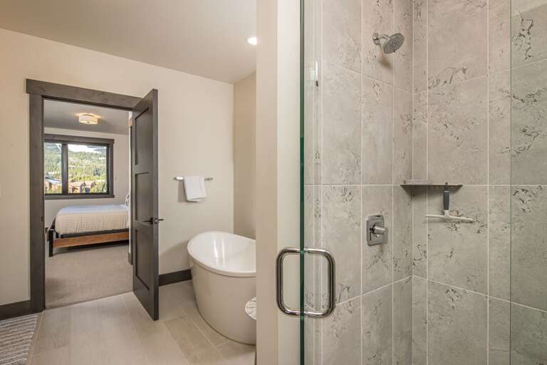 Spa-like bathroom featuring a sleek freestanding soaking tub and glass-enclosed walk-in shower. | Main Level