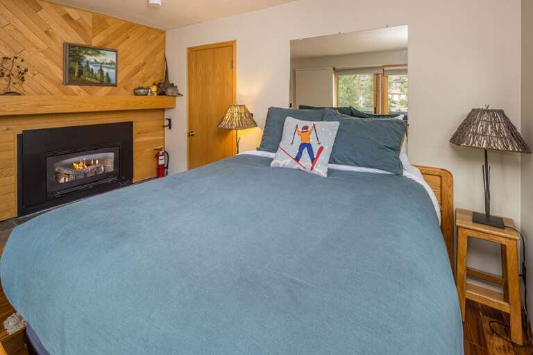 Comfortable queen-sized bed with warm fireplace | Primary Bedroom