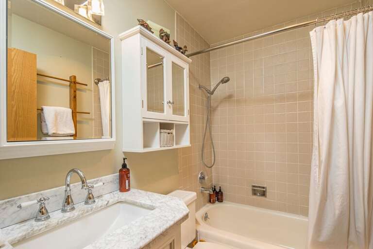 Single vanity and tub/shower combo in primary bathroom | Main Level