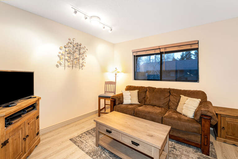 Living Room With Brown Sofa, Wooden Furniture, And Window View