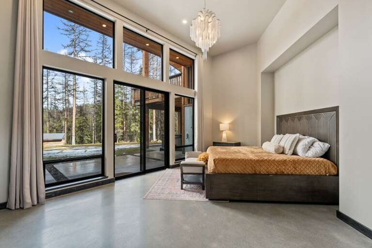 Spacious Room With Large Windows, Elegant Bed, And Forest View