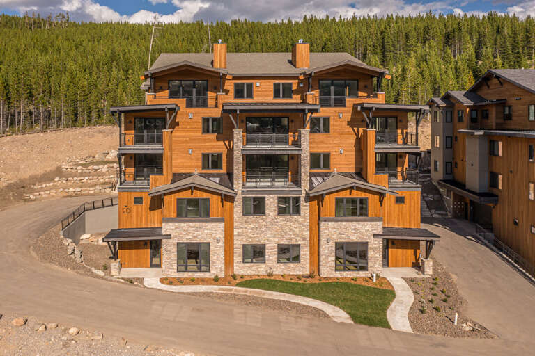 Modern building with wood siding and mountain forest backdrop I Outside View