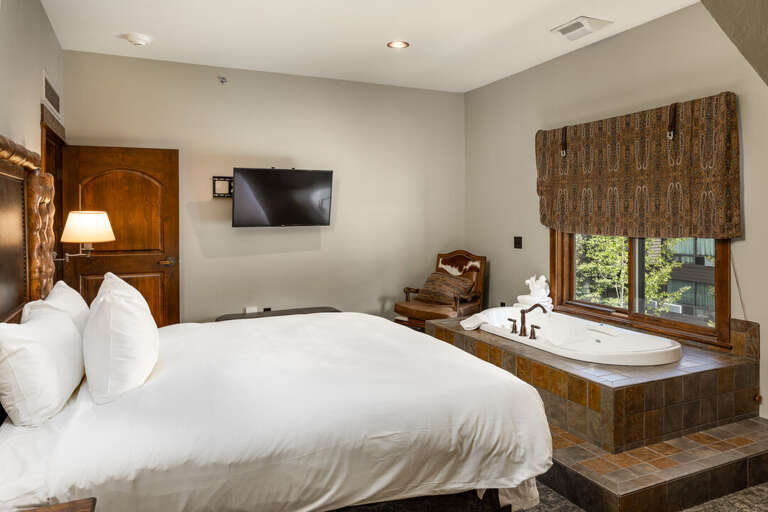 Primary bedroom with soaking jetted tub and TV to wind down from a day at the slopes | Main Level