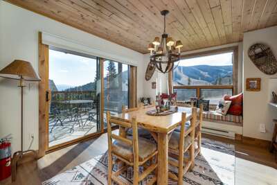 Gather around the wood dining table under the chandelier with mountain views through the windows.
