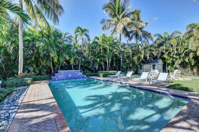 Tropical Backyard With Swimming Pool And Lounge Chairs Surrounded By Palm Trees Tropical Backyard With Swimming Pool And Lounge Chairs Surrounded By Palm Trees