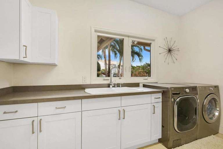 Laundry Room With White Cabinets, Washer, And Dryer By Window Laundry Room With White Cabinets, Washer, And Dryer By Window