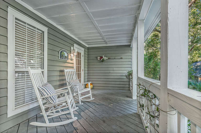 Wooden Porch With White Rocking Chairs, Grey Siding, And Greenery