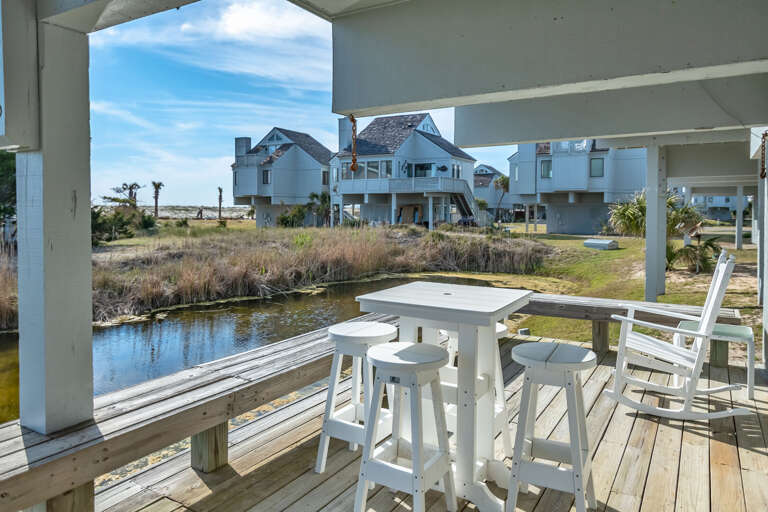 View From Wooden Waterfront Deck Showing Chairs And Houses