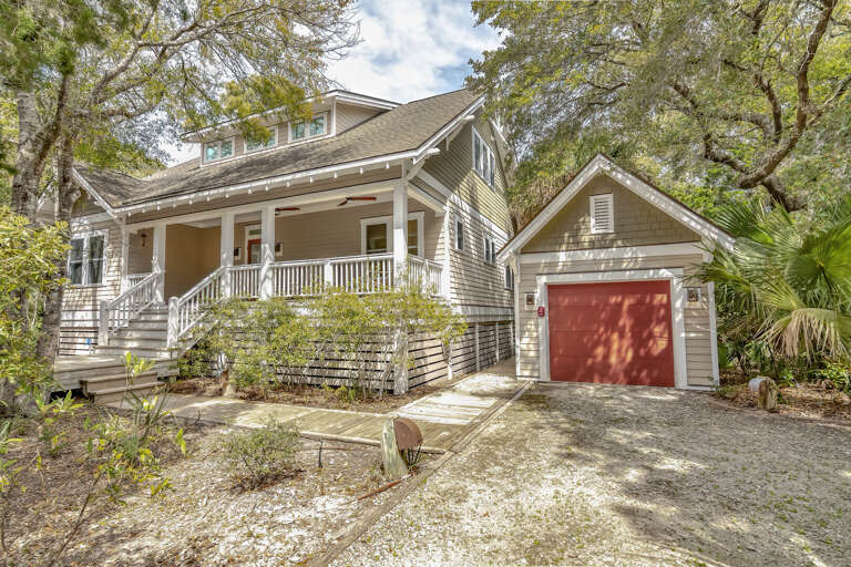 Sunlit Structure Surrounded By Serene Greenery, With A Red Garage Door
