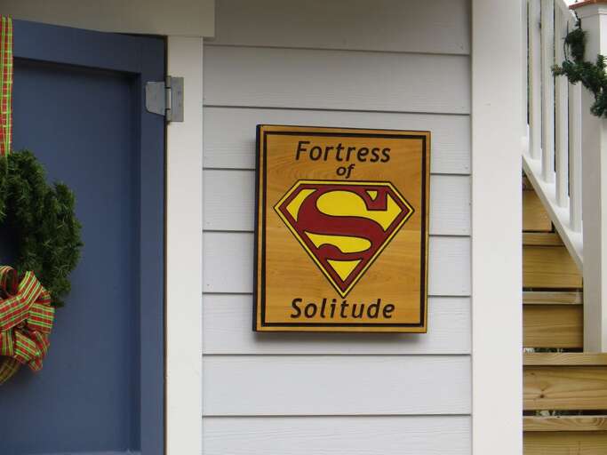 Sign Showing Fortress Of Solitude With Superman Symbol On Building Side
