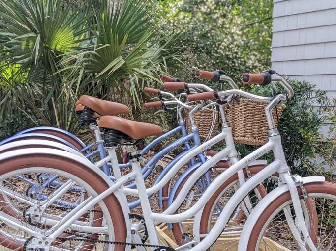 Bicycles By Building, Baskets Attached, Amidst Greenery
