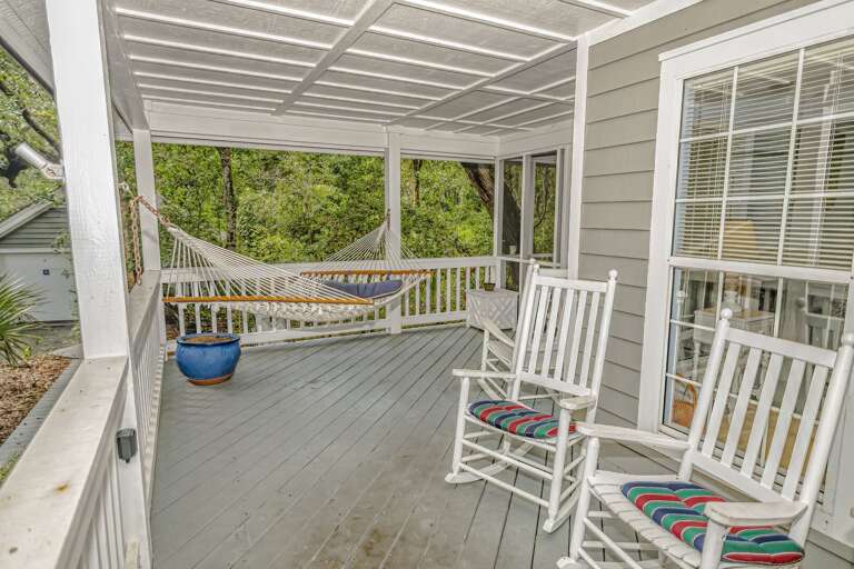 House Porch With Hammock And Wooden Chairs, Surrounded By Greenery