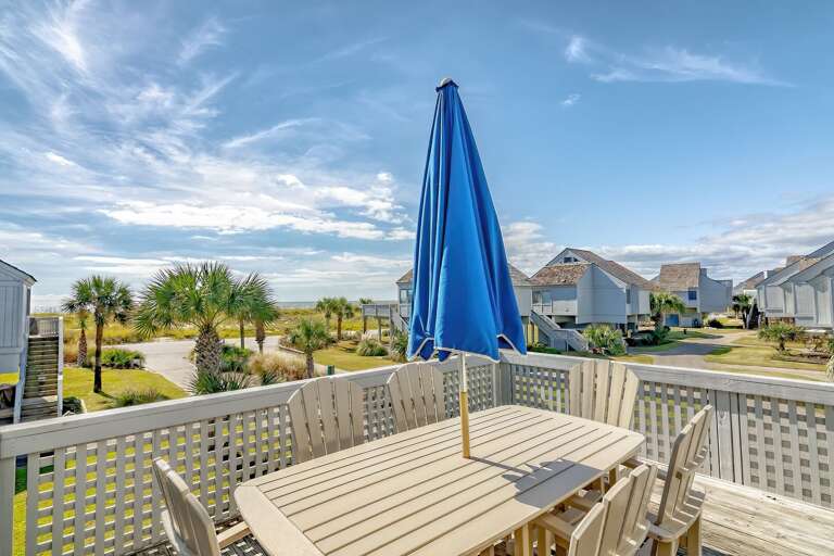 Balcony View With Blue Umbrella Overlooking Beachside Buildings