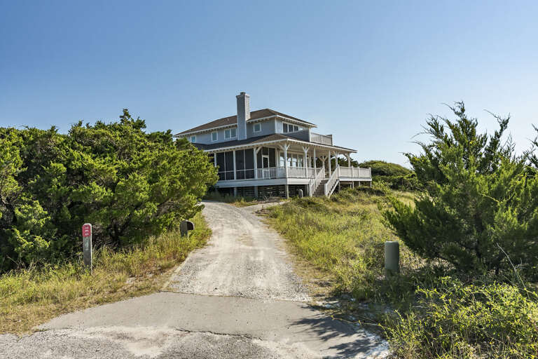 Large Beachside House Nestled Among Shrubs With Sunlit Skies