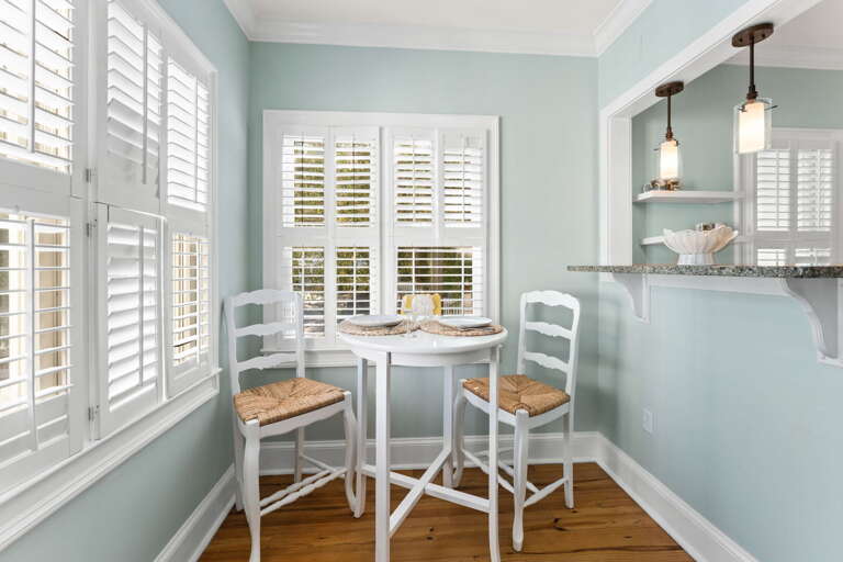 Light-filled Breakfast Nook With White Chairs And Table Under Pendant Lights
