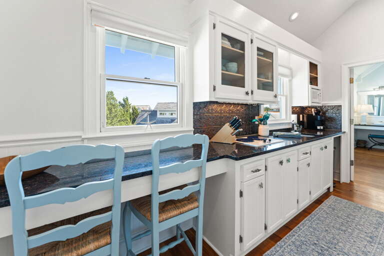 Bright Beach-themed Kitchen With Blue Chairs And White Cabinets In A Vacation Rental