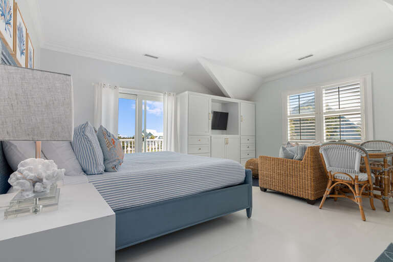 Bright Bedroom With Big Bed, Balcony Access, Rattan Seating, And Sea Glimpses