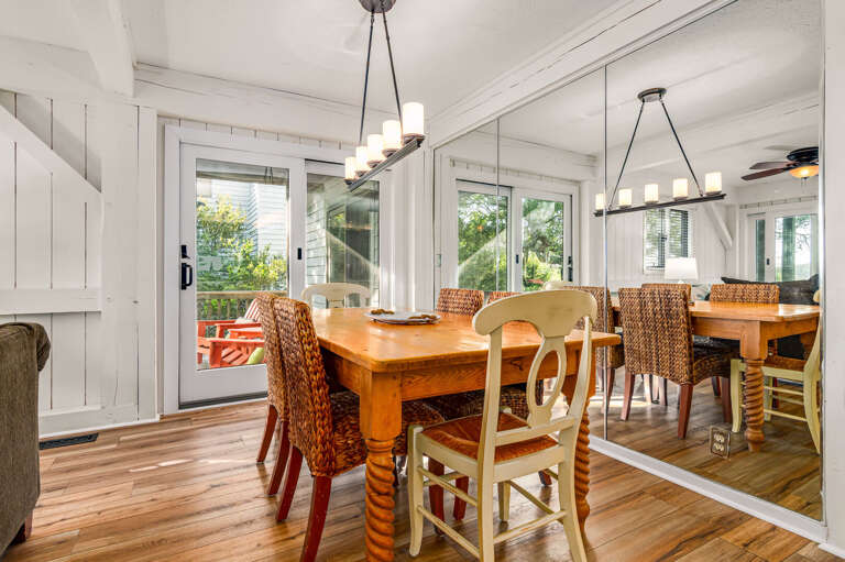 Bright Dining Space With Wooden Floors And White Walls, Featuring A Table And Hanging Lamps