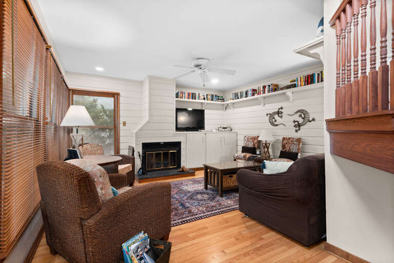 Living Room With Fireplace, Armchairs, Bookshelves, And Ceiling Fan