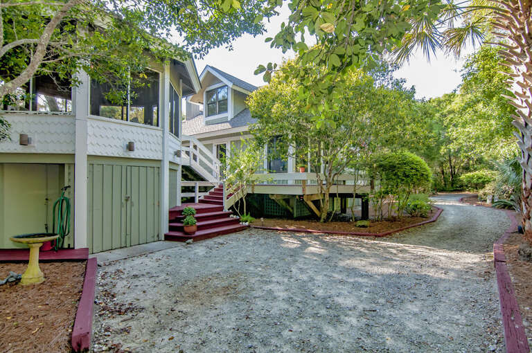 Gravel Driveway Leading To Green And White House Nestled Among Trees