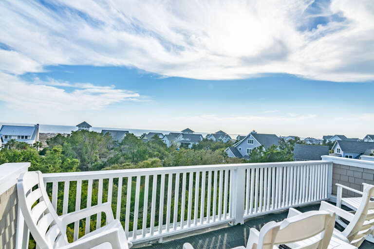 Balcony View Of A Breezy Seascape, Chairs Overlooking Clustered Cottages