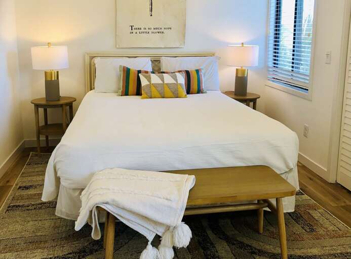 Bedroom With Bright Bedding And Bench, Vibrant Pillows, Framed Text Above Bed