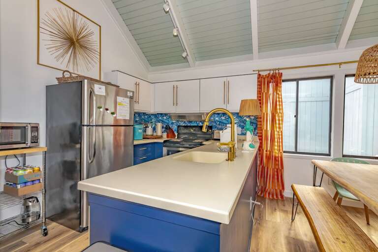 Bright Kitchen With Blue Island And Bamboo Bench, Steel Fridge, Sunburst Wall Decor