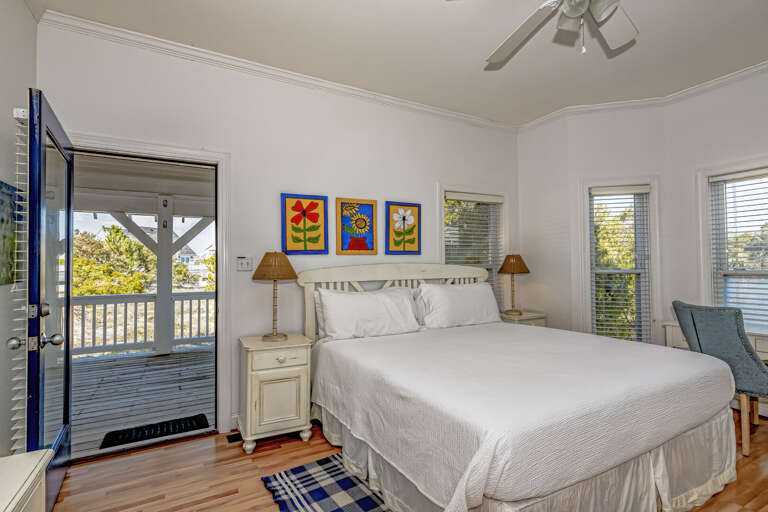 Bright Bedroom With Balcony Access, White Walls, And Colorful Artwork