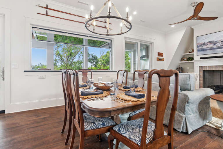 Brightly-lit Dining Space With Wooden Furniture And Ceiling Fan, Fireplace In The Background