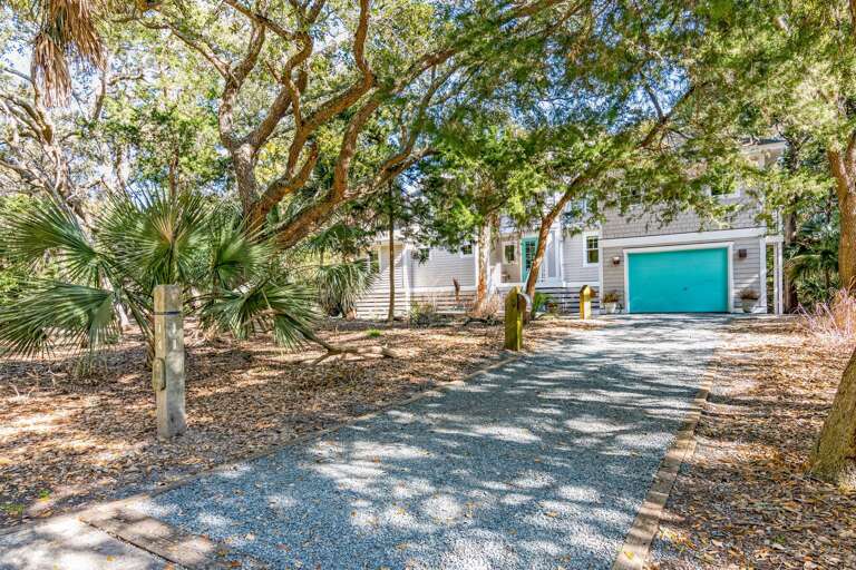 Home Hidden By Leafy Trees With Blue Garage Door In Dappled Sunshine