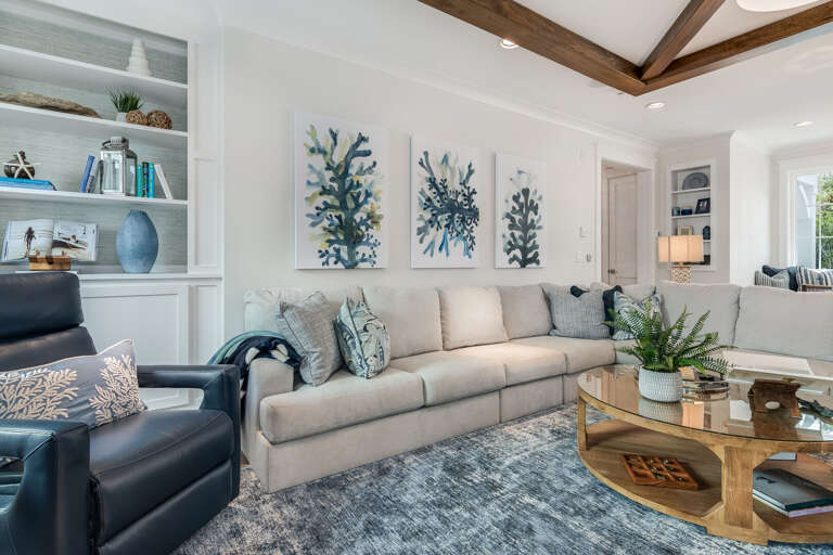 Brightly Lit Living Room With Beige Sofa, Black Chairs, And Blue Decor Details