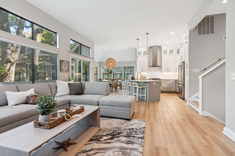 Spacious Living Space Showing Sofas, Kitchen, And Dining Area With High Ceilings And Hardwood Floors